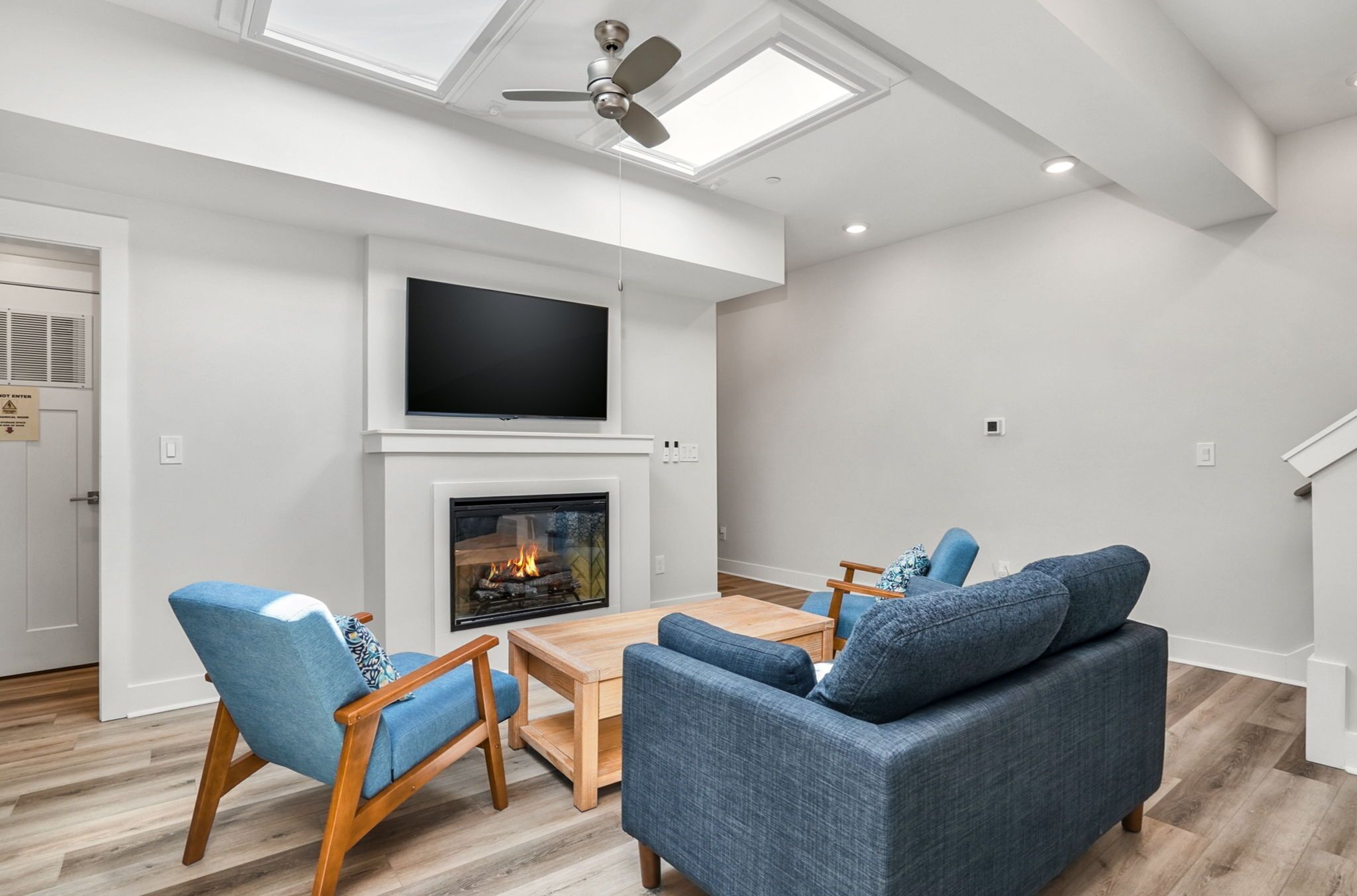 Un salon moderne doté d’une cheminée, d’un téléviseur à écran plat et d’un ventilateur de plafond.