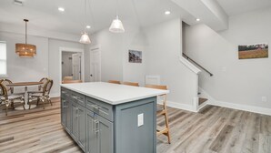 A spacious kitchen with a central island, wooden flooring, and pendant lighting.