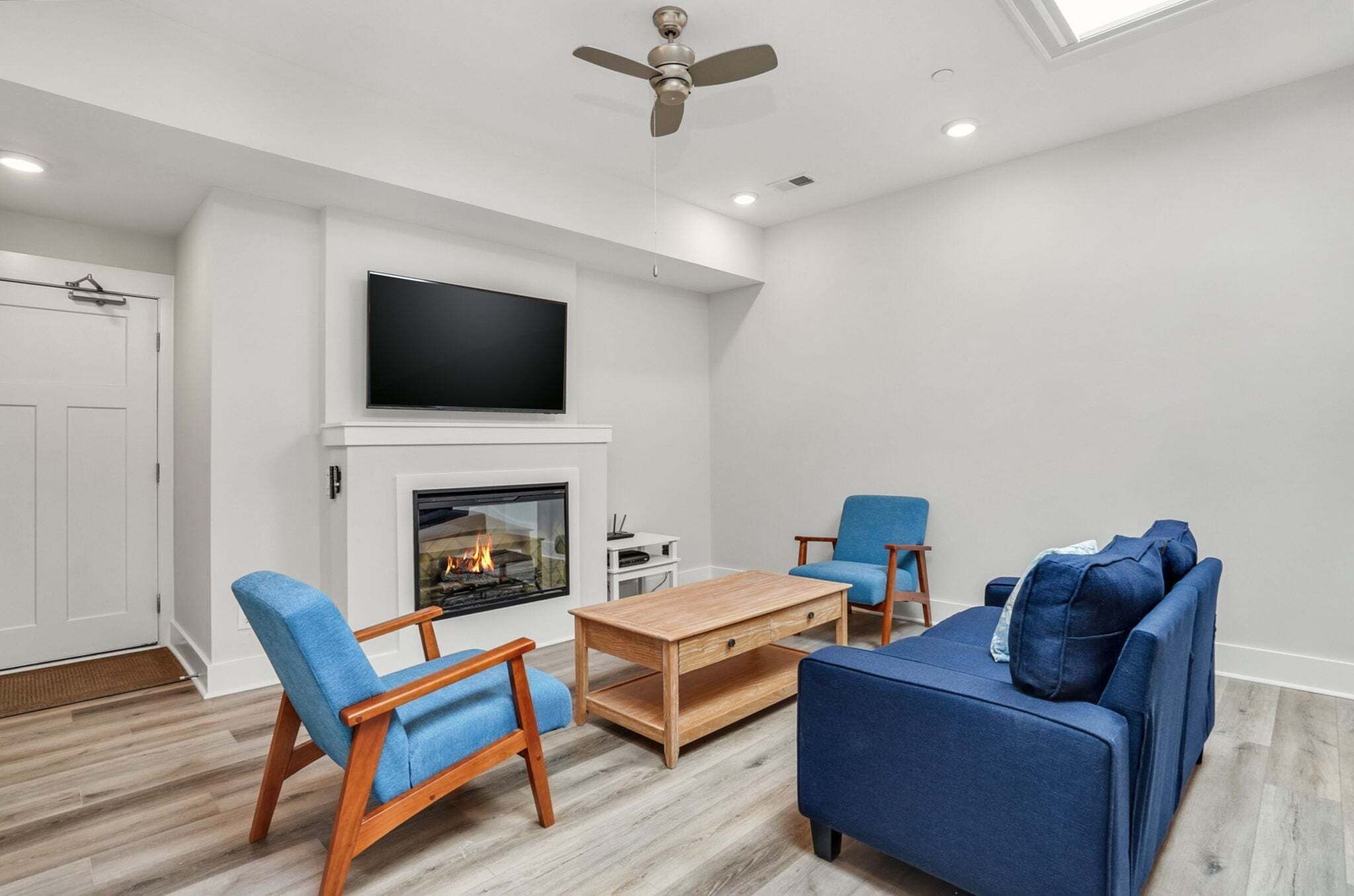 Een moderne woonkamer met een open haard, blauw meubilair en een flatscreen televisie.