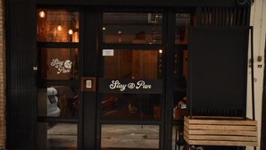 A restaurant entrance with a 'Stay @ Pan' sign, wooden interior, and a shoe rack outside. - STAY AT PAN (Bangkok)