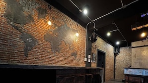 A bar area with a brick wall, hanging lights, and a wooden table with a vase. - STAY AT PAN (Bangkok)