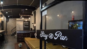 A cozy bar area with a television, a 'Stay @ Pan' sign, and a brick wall. - STAY AT PAN (Bangkok)