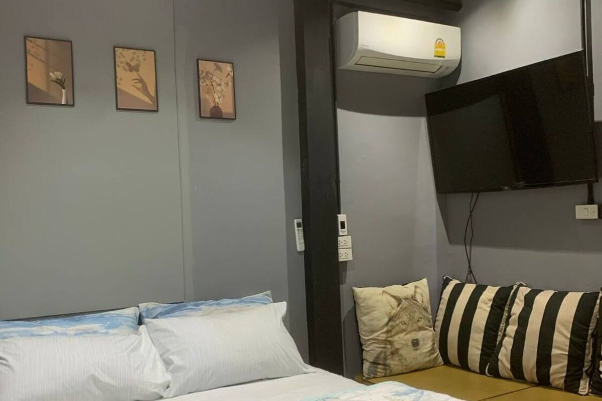 A hotel room with a bed, a TV mounted on the wall, and three framed pictures on the wall.