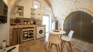 Una cocina compacta con un arco de piedra, una lavadora y un comedor con dos sillas.