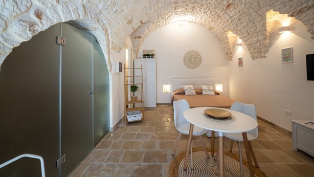 Una habitación acogedora con techo de piedra, una cama con almohadas, una mesita y una silla.