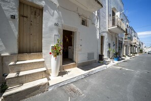 A white building with a wooden door, numbered 60, and a small entrance.