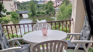 A balcony with a round table and white chairs, overlooking a river and greenery. - Bougenay vacation village with free swimming pool from May to mid-September (Talmont-Saint-Hilaire)