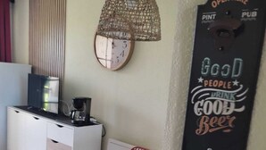 A dining area with a table, chairs, a hanging light fixture, a clock, and a wall-mounted sign. - Bougenay vacation village with free swimming pool from May to mid-September (Talmont-Saint-Hilaire)