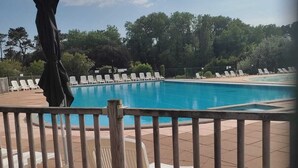 A swimming pool with white lounge chairs and a wooden fence. - Bougenay vacation village with free swimming pool from May to mid-September (Talmont-Saint-Hilaire)