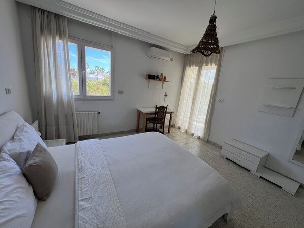 Une chambre d’hôtel avec un grand lit, un bureau, une chaise et une fenêtre avec des rideaux.
