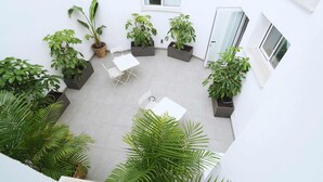 A courtyard with potted plants, a white table, and chairs. - La Inmaculada Alojamientos (Málaga)