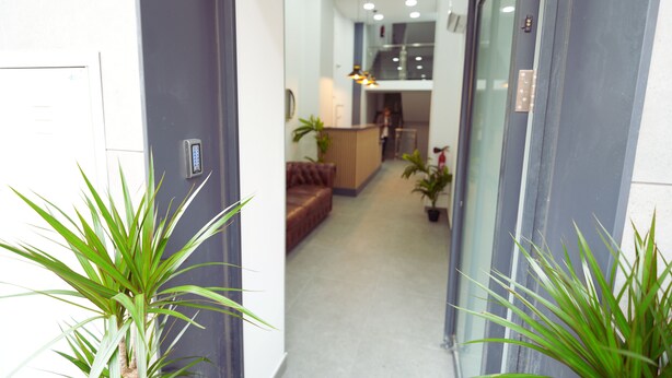 A hallway with a reception desk, a brown leather sofa, and potted plants. - La Inmaculada Alojamientos (Málaga)