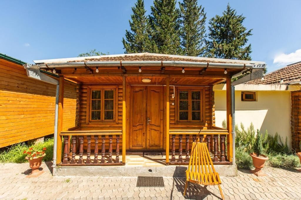A wooden cabin with a porch, a door, and windows.