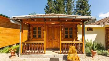 A wooden cabin with a porch, a door, and windows.