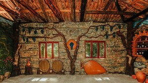 A rustic room with stone walls, wooden beams, and a tree mural. - Eco cottages (Tsqaltubo)