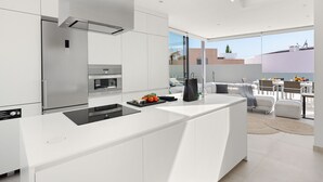 Une cuisine moderne dotée d’un îlot central, d’appareils électroménagers en acier inoxydable et offrant une vue sur la ville grâce à de grandes fenêtres.