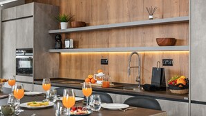 A modern kitchen with a wooden backsplash, built-in appliances, and a breakfast setup with orange juice and fruits. - Villa Origen Exclusive (Adeje)