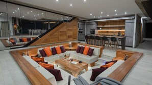 A spacious living area with a central coffee table, sofas, and a kitchen in the background. - Villa Origen Exclusive (Adeje)