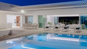 Un’area piscina interna moderna con sedie a sdraio e una zona pranzo.