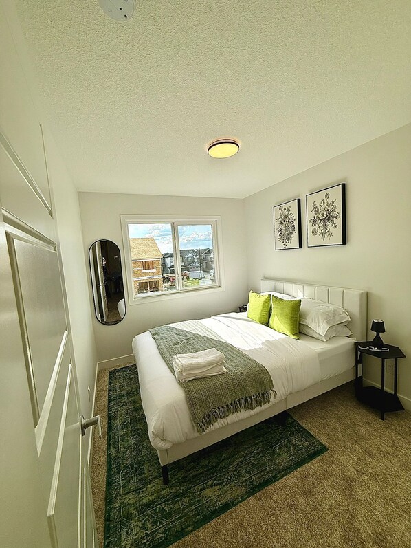 A bedroom with a bed, a nightstand, a mirror, and two framed pictures on the wall.