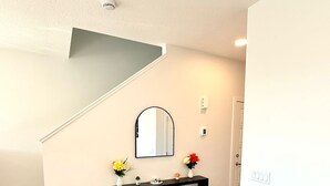 A modern living room with a black console table, a mirror, and a staircase.