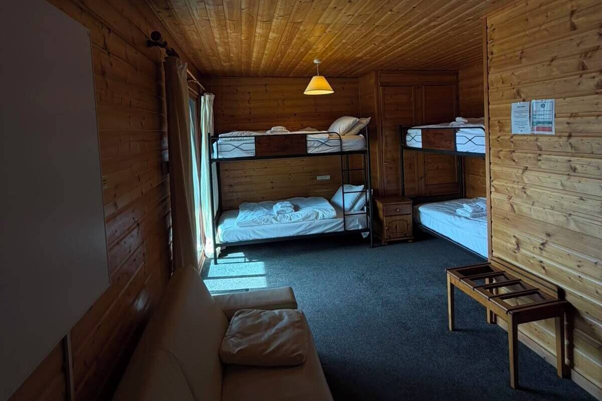 Une cabine équipée de lits superposés, d’un canapé, d’une table et d’un luminaire suspendu.