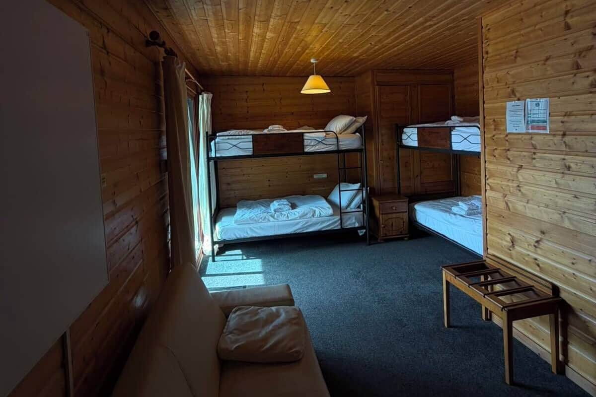 Una cabaña con literas, un sofá, una mesa y una lámpara colgante.