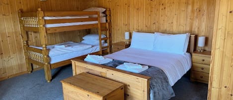 Un dormitorio de estilo cabaña con literas, un aparador de madera y dos mesitas de noche con lámparas.