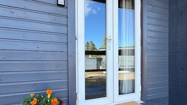Een huis met een schuifdeur, een bloempot en een deurmat.
