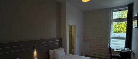 Ein Hotelzimmer mit zwei Betten, einem Schreibtisch, einem Stuhl und einem Fenster mit Blick.