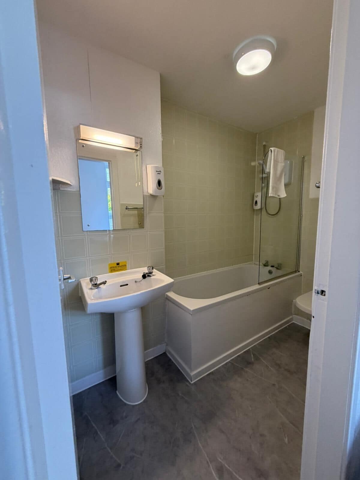 A bathroom with a sink, mirror, and shower.