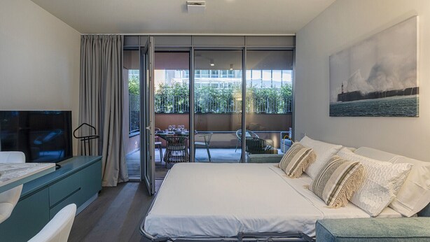A modern hotel room with a bed, a TV, a balcony with a view of greenery, and a painting on the wall. - Waterfront Dream by Wonderful Italy (Genova)