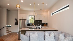 A modern kitchen with a central island, stainless steel appliances, and pendant lighting. - Turf ROOFTOP w Games and more in Heart of Wilmington! Rent Multiple or One Unit! Unit C (Wilmington)