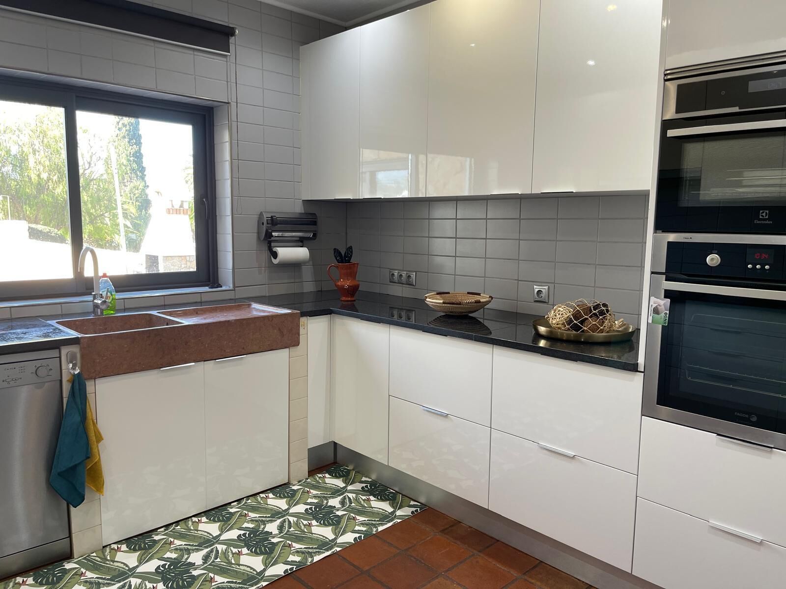 Una cocina moderna con gabinetes blancos, encimera negra y horno integrado.
