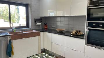 Una cocina moderna con gabinetes blancos, encimera negra y horno integrado.