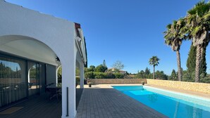 Un espace piscine extérieur moderne, doté d’une terrasse, d’un coin salon abrité et d’un mur en pierre.