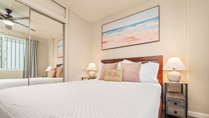 A hotel room with a large bed, two bedside tables with lamps, a wall-mounted painting, and a window with curtains.