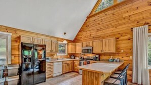 A modern kitchen with wooden cabinetry, a stainless steel refrigerator, a microwave, and a large island with bar stools. - 3 Bedrooms, 1 Flex Room, 4 Bathrooms!  Come Visit 'Lake-A-Licious'! (Huddleston)