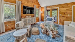 A cozy cabin interior with wooden walls, a glass coffee table, a sofa, and a TV mounted on the wall. - 3 Bedrooms, 1 Flex Room, 4 Bathrooms!  Come Visit 'Lake-A-Licious'! (Huddleston)