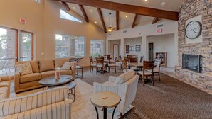 A spacious indoor area with a stone fireplace, multiple seating arrangements, and a ceiling fan. - Golden Golf & Mt VIEWS, Golfers/Hikers Paradise, Comm Htd Salt POOL & Spa (Gold Canyon)