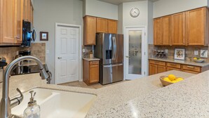 A modern kitchen with stainless steel appliances, wooden cabinets, a granite countertop, and a clock on the wall. - Golden Golf & Mt VIEWS, Golfers/Hikers Paradise, Comm Htd Salt POOL & Spa (Gold Canyon)