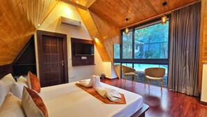 Un dormitorio con techo de madera, una cama grande con almohadas, un televisor y una ventana con cortinas.