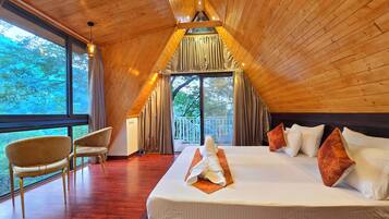 Un dormitorio amplio con una cama grande, techo de madera y vistas al exterior a través de un ventanal.