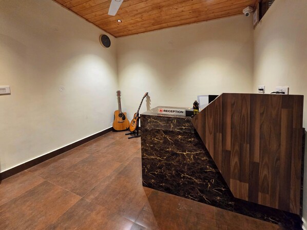 A reception area with a wooden reception desk, a marble staircase, and a guitar against the wall. - Musical Paradise Kasauli (Kasauli)