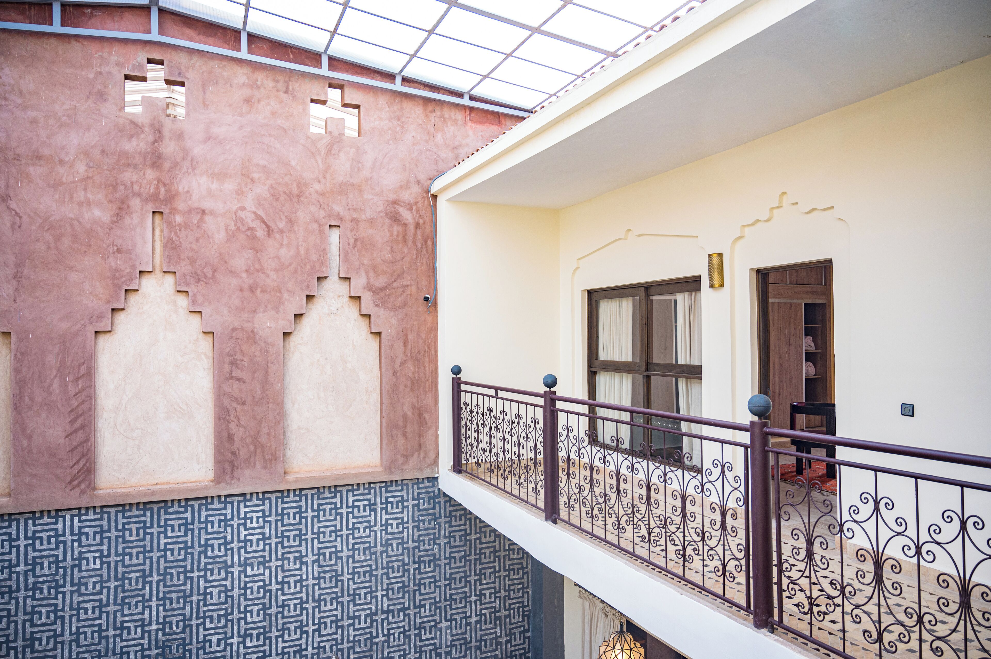 A building with a patterned exterior wall, a balcony with decorative railing, and a door with a window.