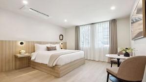 A modern hotel room with a large bed, bedside table, and a small round table with a chair. - Casa Riviera 1 - Boutique Suites (Santa Barbara)