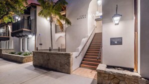 A hotel entrance with a staircase, stone walls, and a palm tree. - Casa Riviera 1 - Boutique Suites (Santa Barbara)