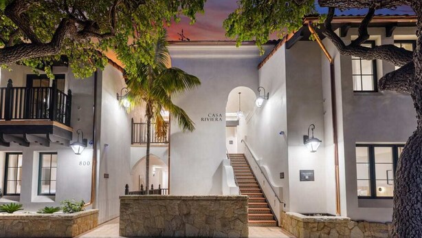 A modern hotel interior with a central staircase, stone planters, and a sign reading "CASA RIVIERA". - Casa Riviera 1 - Boutique Suites (Santa Barbara)