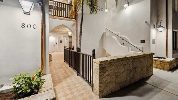 A hotel lobby with a stone reception desk, a staircase, and a balcony. - Casa Riviera 3 - Boutique Suites (Santa Barbara)