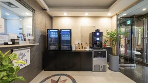 A reception area with a counter, two beverage dispensers, a coffee machine, and a potted plant. - ANYANG IT CENTRO HOTEL (Anyang)
